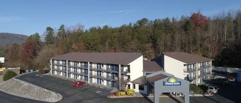A Days Inn with a multi-story building, parking lot, and surrounding forested area.