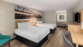 Habitación de hotel con dos camas, un escritorio, un televisor y un ventanal grande.