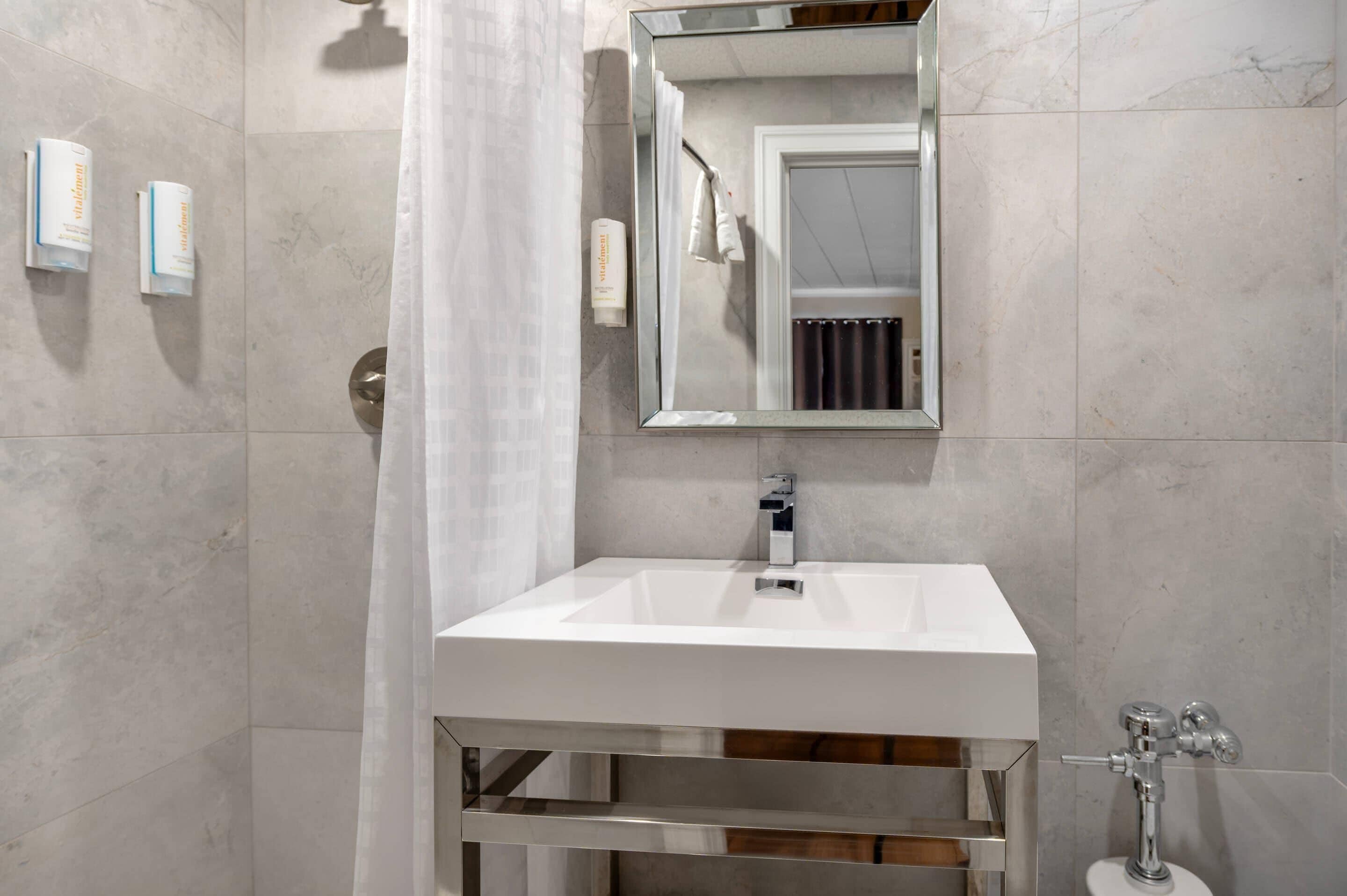 Een moderne badkamer met een wit wastafel, een spiegel en een douchegordijn.