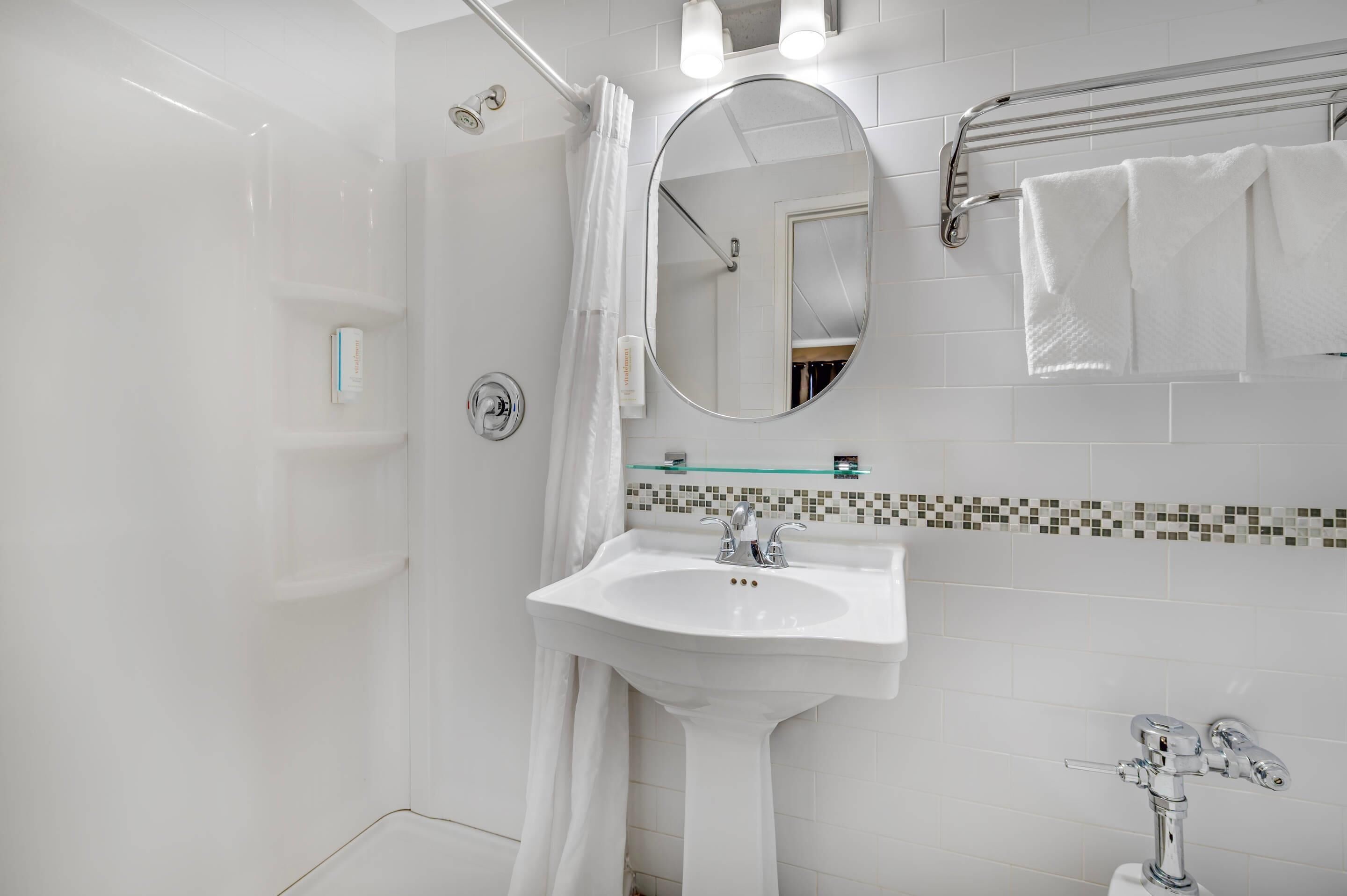 Casa de banho moderna com cabine de duche, lavatório com espelho e suporte para toalhas.