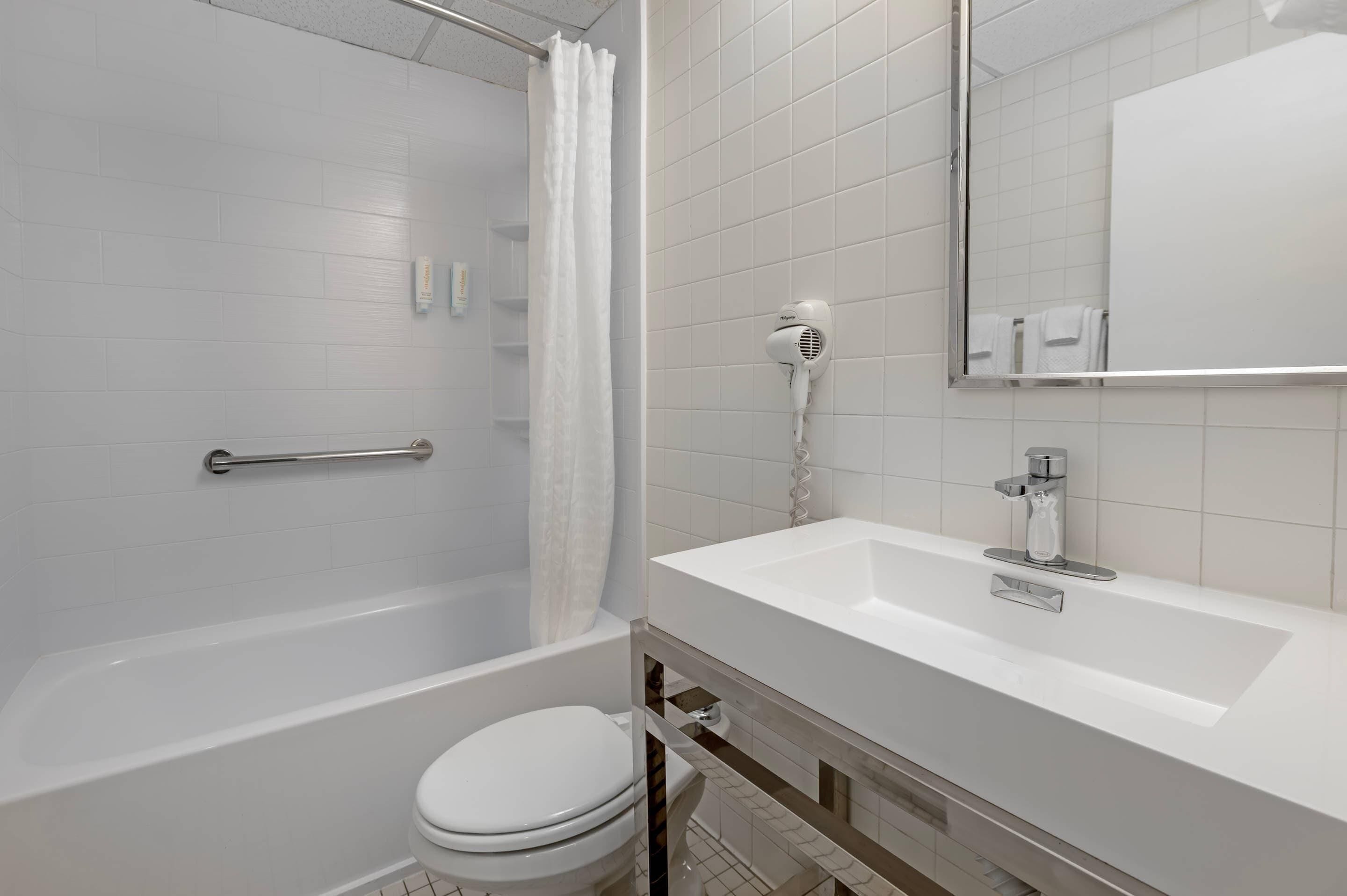 Un baño moderno con bañera, inodoro y lavabo con espejo.