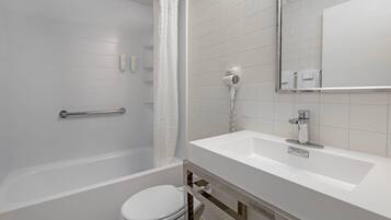 Un baño moderno con bañera, inodoro y lavabo con espejo.