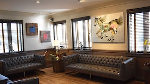 A spacious living room with a large sofa, a coffee table with decorative items, and artwork on the walls. - East Norwich Inn (East Norwich)