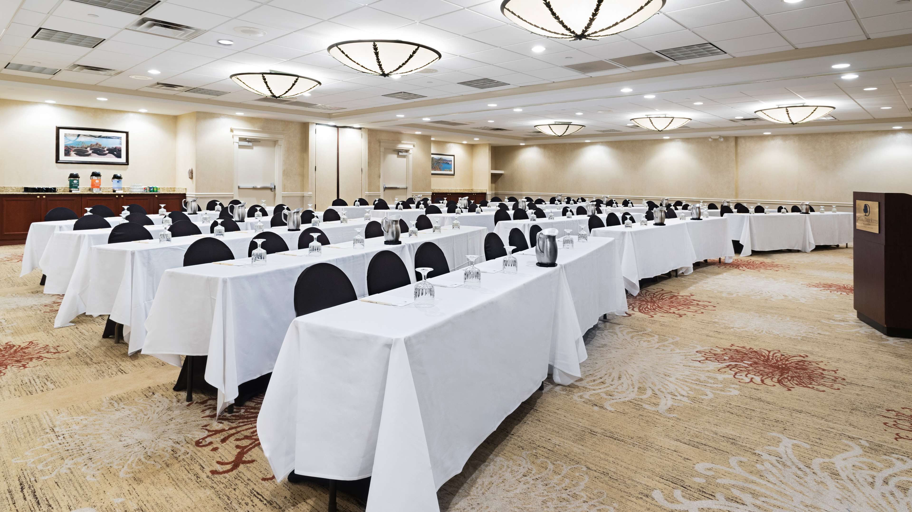A conference room with rows of tables, chairs, and a podium.