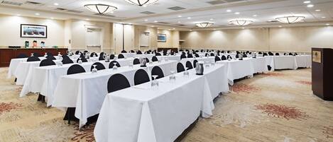 A conference room with rows of tables, chairs, and a podium.