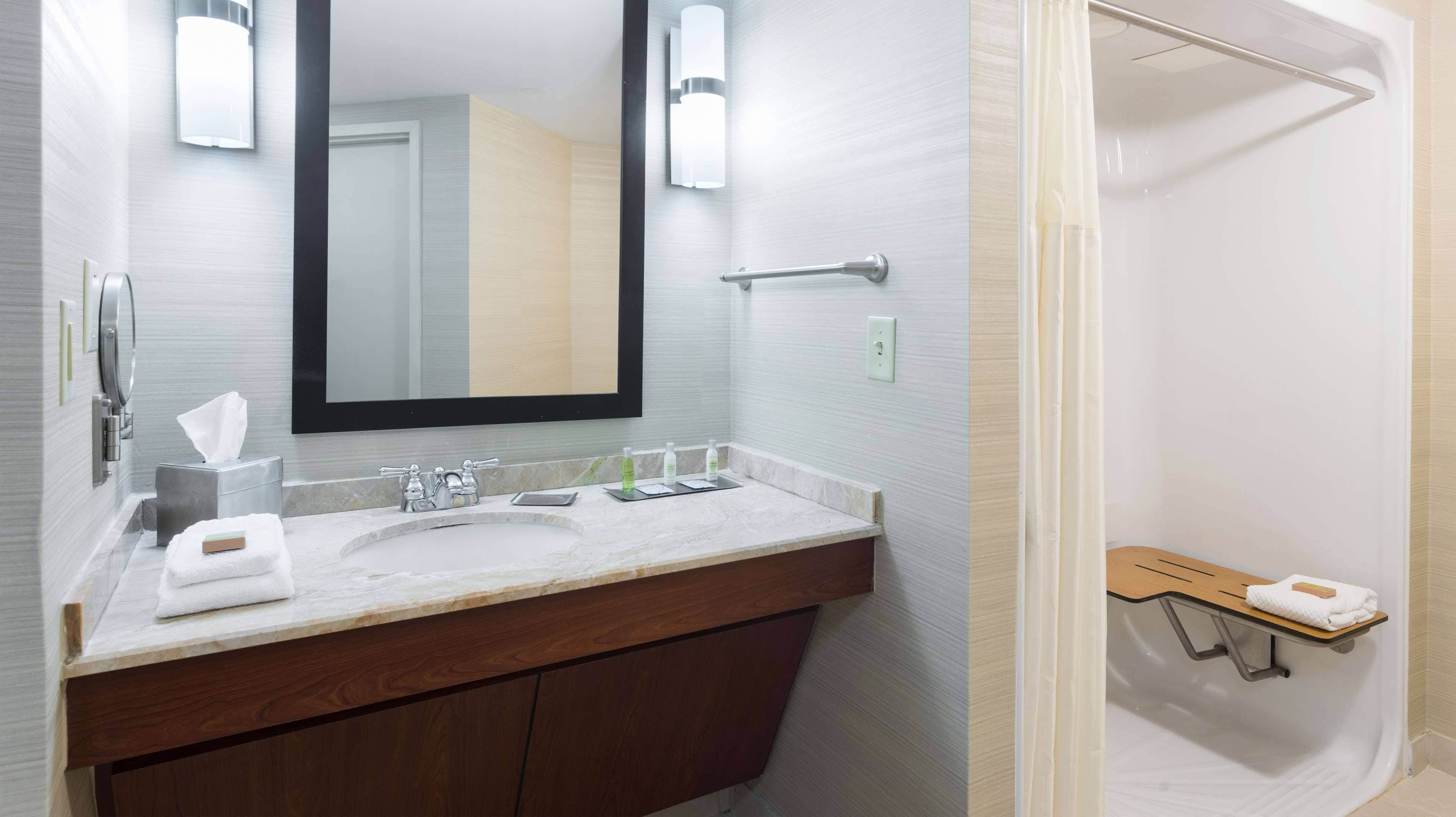A bathroom with a marble sink, a mirror, a towel rack, and a shower area.