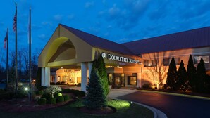 Un hotel DoubleTree Suites con entrada despejada, palos de señales y jardines bien cuidados.