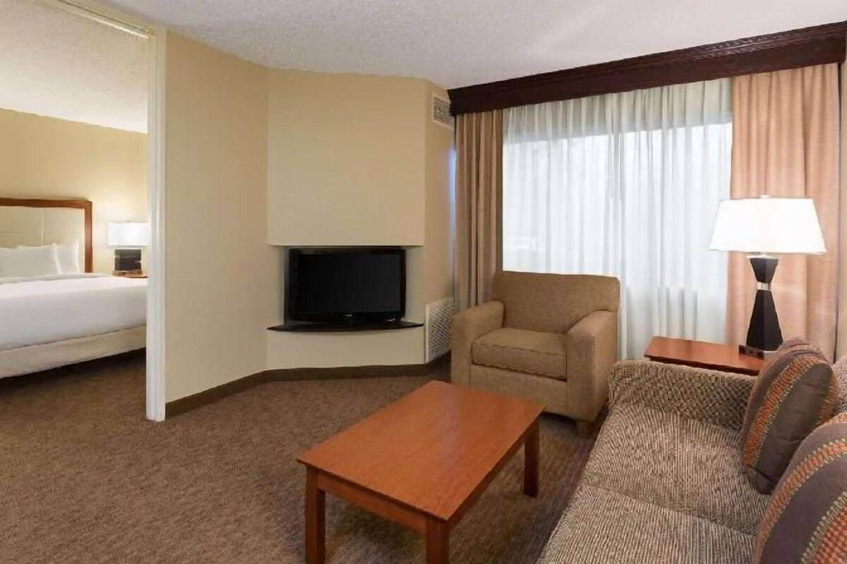 A hotel room with a bed, a television, a sofa, and a coffee table.