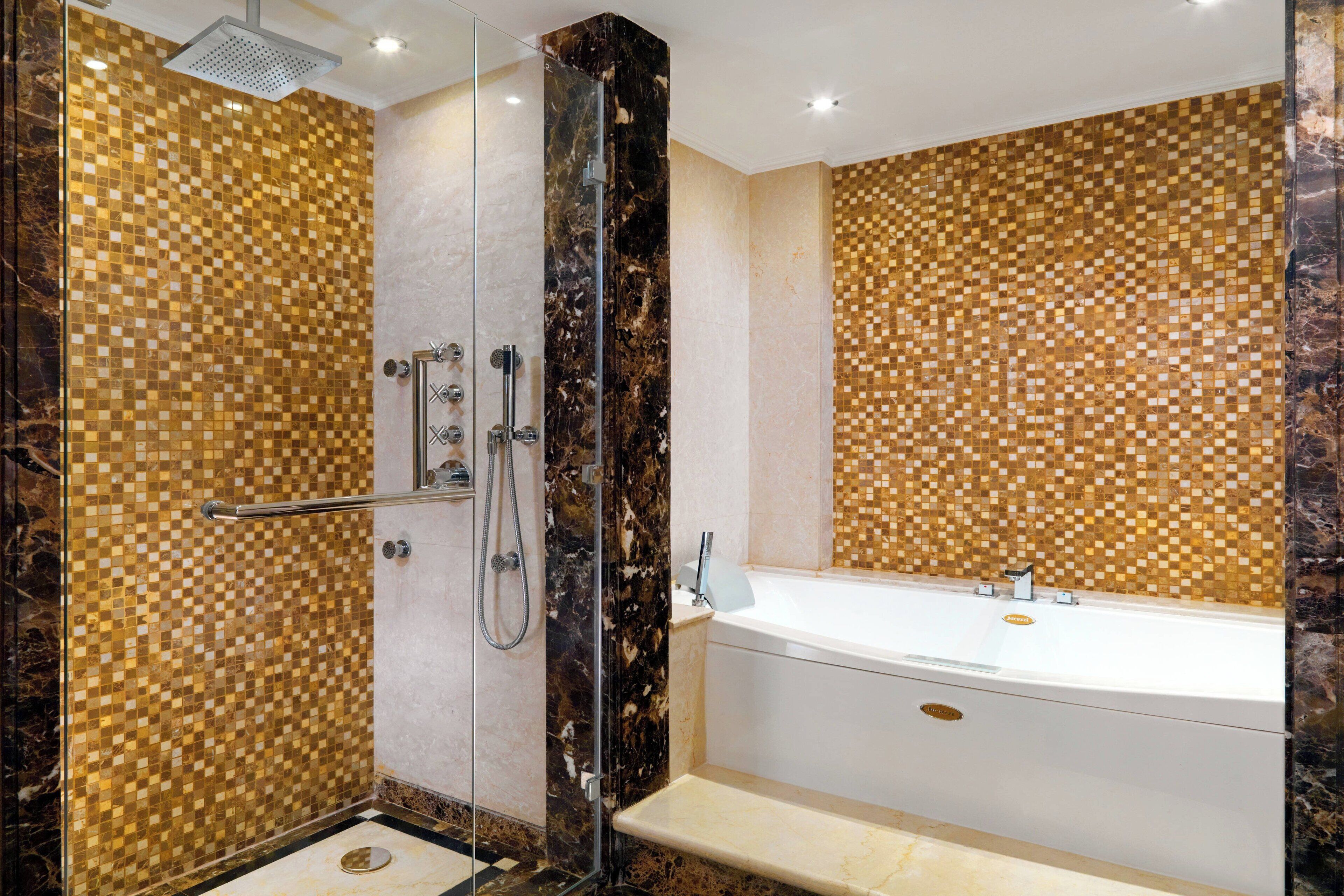 Un baño moderno con ducha de vidrio, bañera independiente y paredes de mosaico.