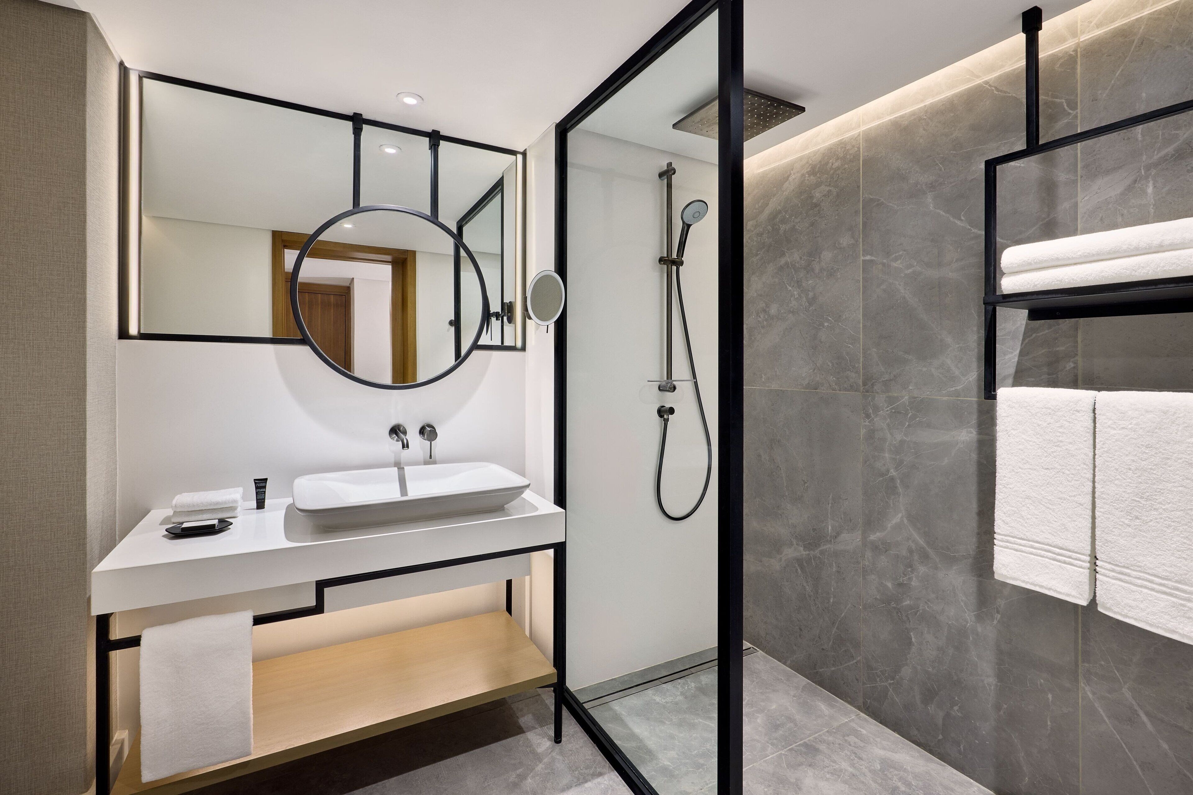Un baño moderno con lavamanos, espejo y toallero blancos.