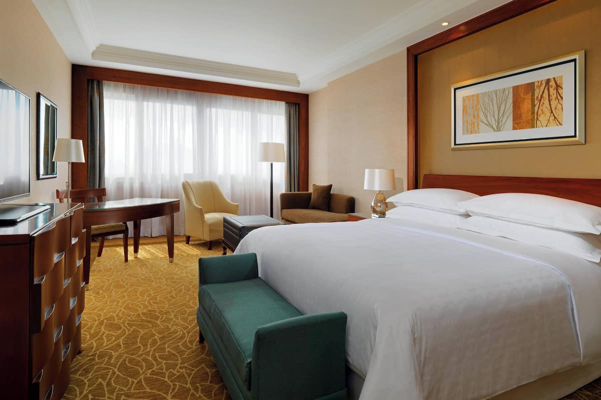 Una habitación de hotel con una cama grande, un escritorio con silla, un sofá y una mesita.