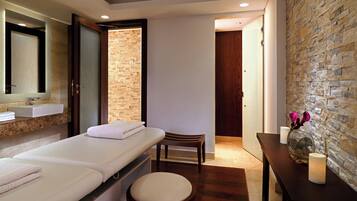Relax in a serene spa room with a large mirror, sink, and wooden bench.