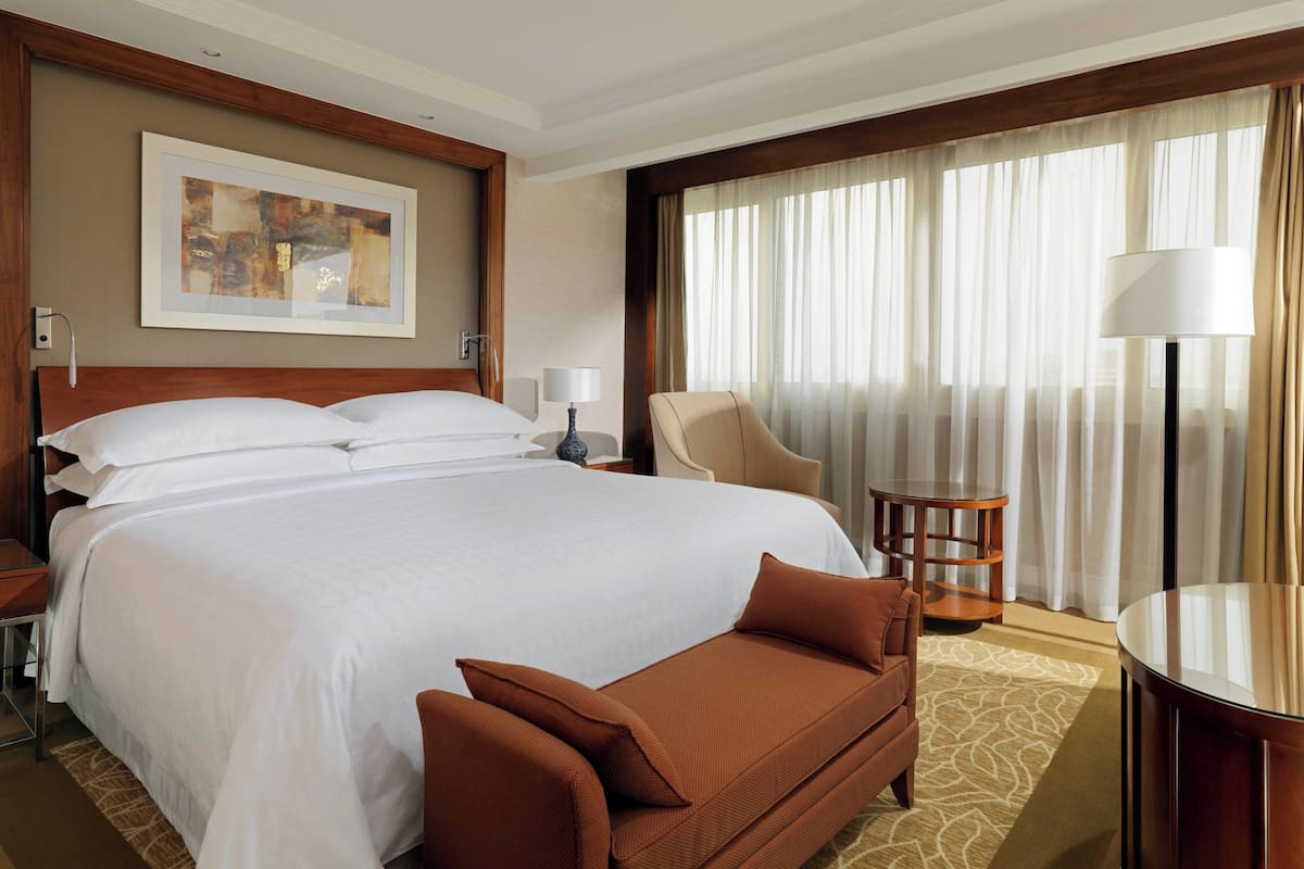 Una habitación de hotel con una cama grande, una silla, una mesa y una lámpara.