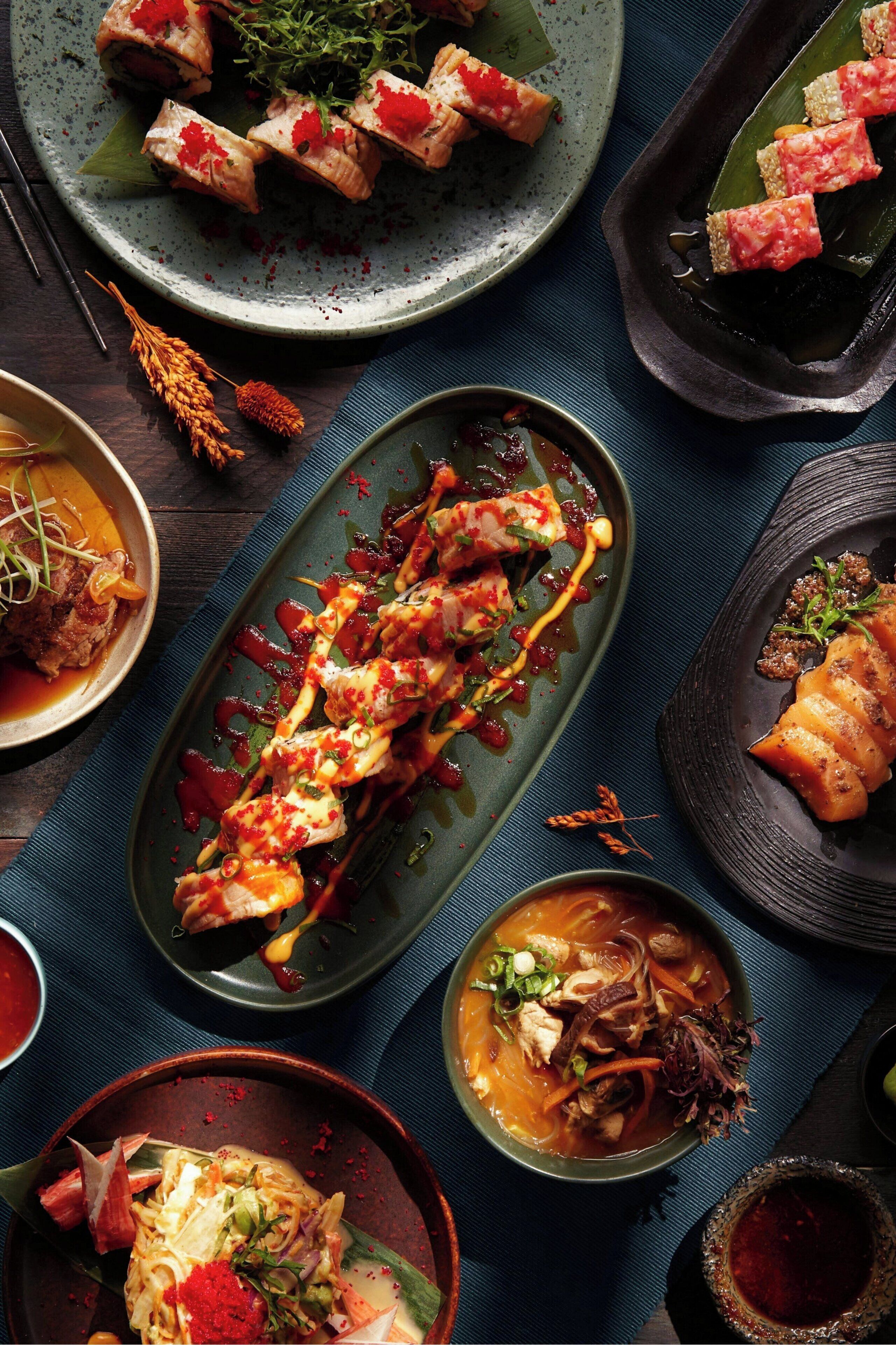 A variety of dishes on plates, including sushi and soup.