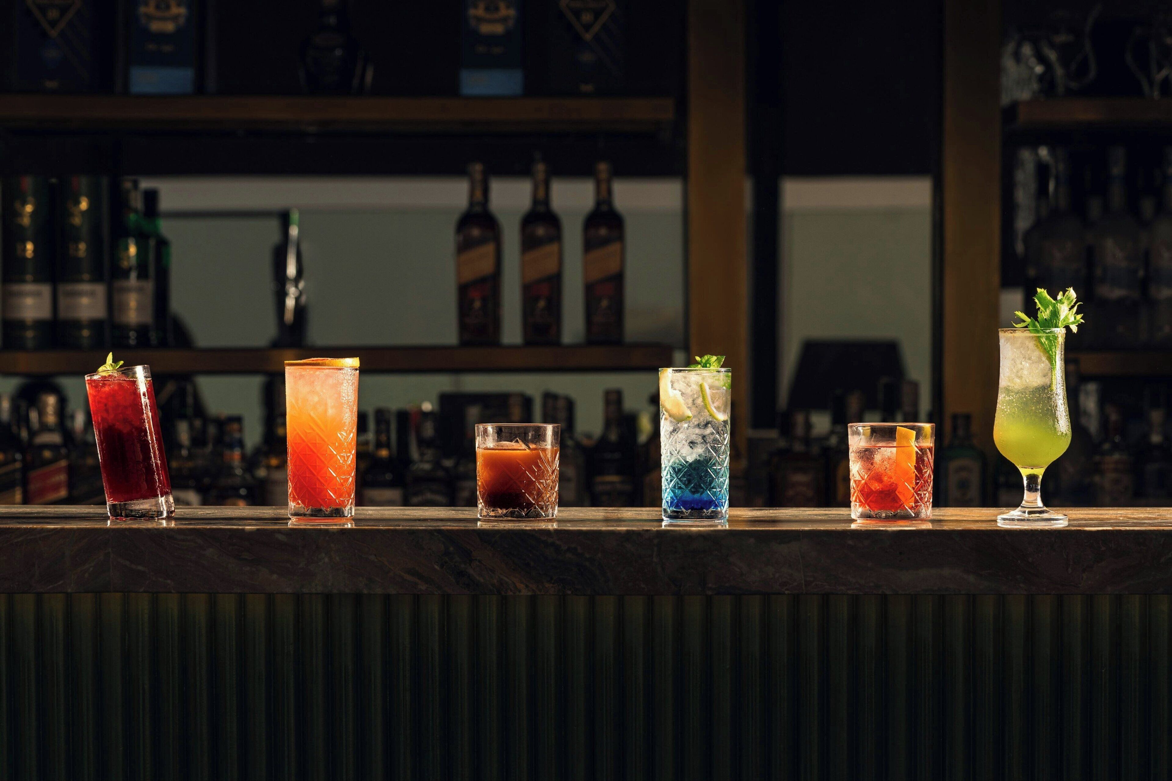 A bar counter with various colorful cocktails.