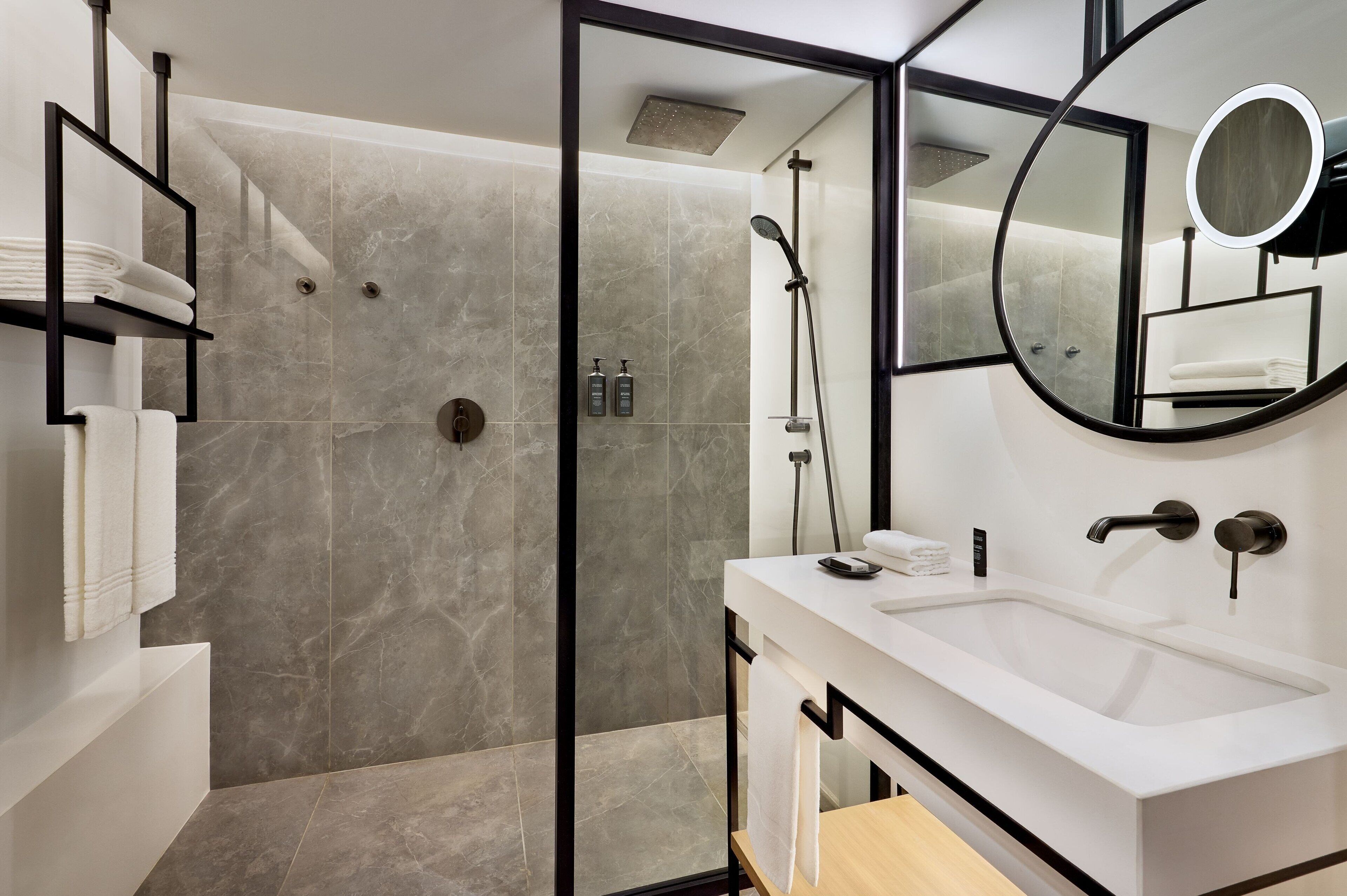A modern bathroom with a shower, a sink, and a mirror.