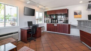 A modern kitchen with a flat-screen TV, a dining area with a bench, and a large window offering a view of the outside.
