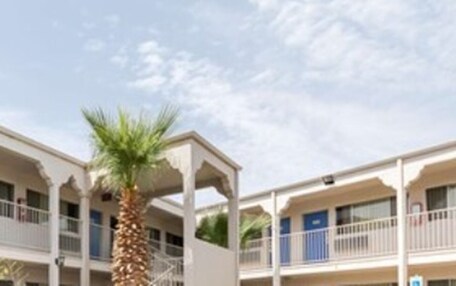 A multi-story hotel with balconies and a palm tree.