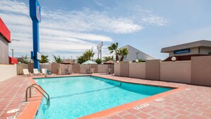 A swimming pool with a 'NO DIVING' sign, surrounded by lounge chairs and a brick patio.