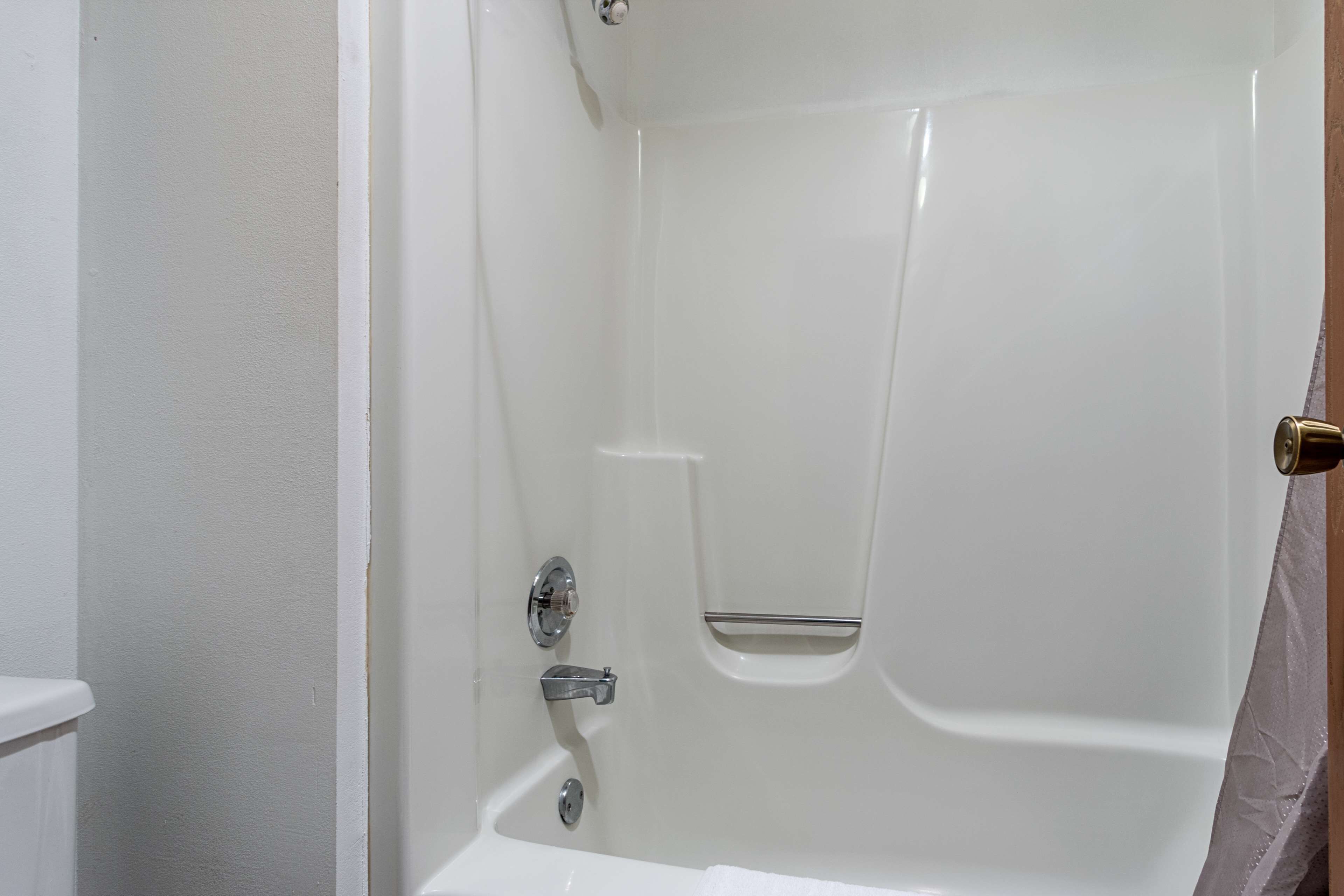 Una bañera blanca con panel de control de ducha y toallero.