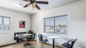A small, well-lit room with a ceiling fan, a table with chairs, and large windows offering a view of the outside. - Motel 6 Wisconsin Rapids, WI (Wisconsin Rapids)