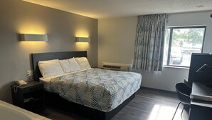 A modern hotel room with a bed, bedside lamps, a desk, a chair, a bathtub, and a window with curtains. - Motel 6 Wisconsin Rapids, WI (Wisconsin Rapids)