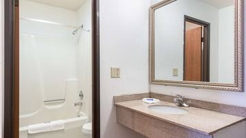 A bathroom with a bathtub, a sink, and a mirror.