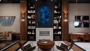 A modern living room with a round wooden coffee table, two leather armchairs, a fireplace, and a large abstract blue artwork on the wall. - The Alloy King of Prussia - a DoubleTree by Hilton (King of Prussia)