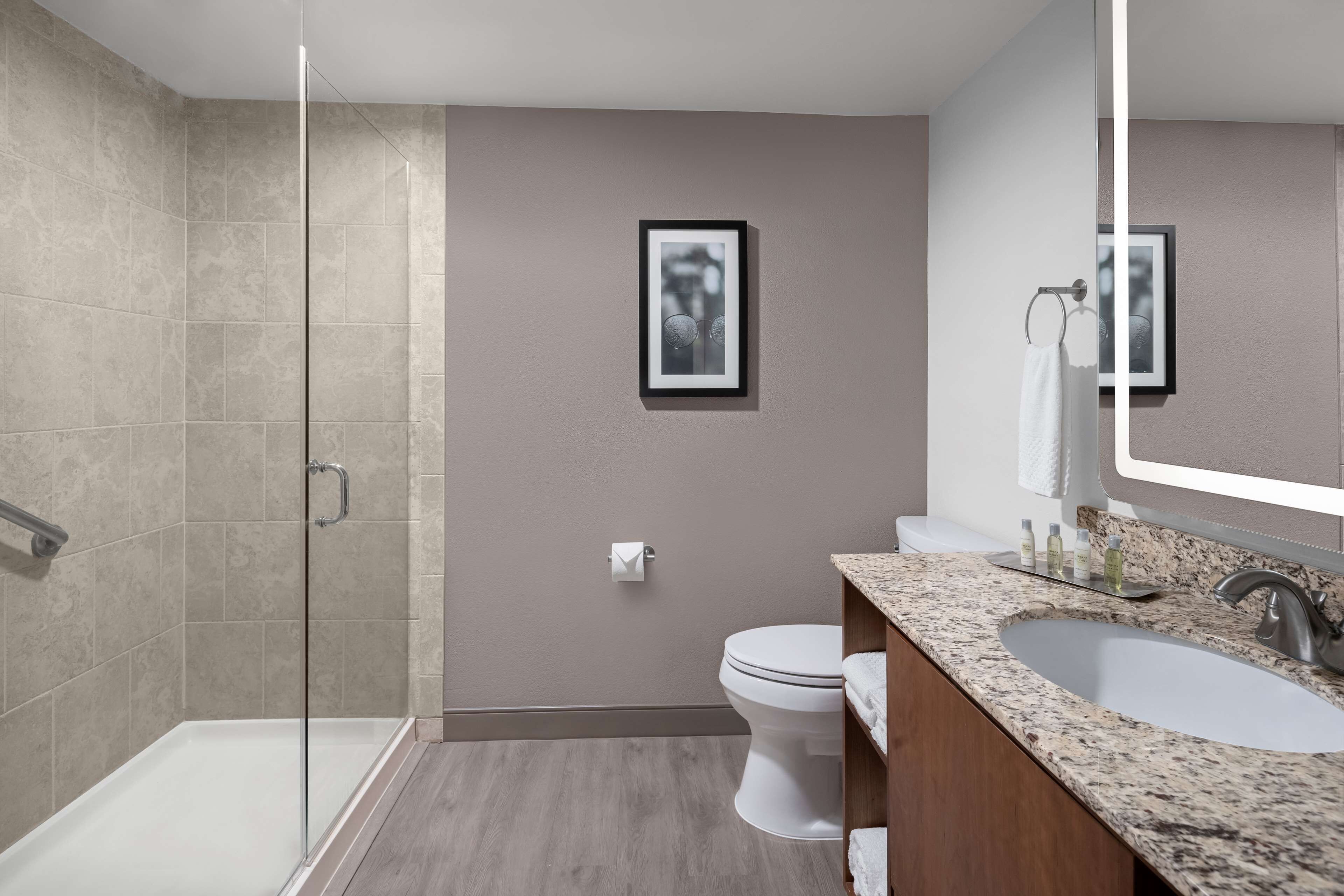 Un baño moderno con cabina de ducha de vidrio, inodoro y tocador doble.
