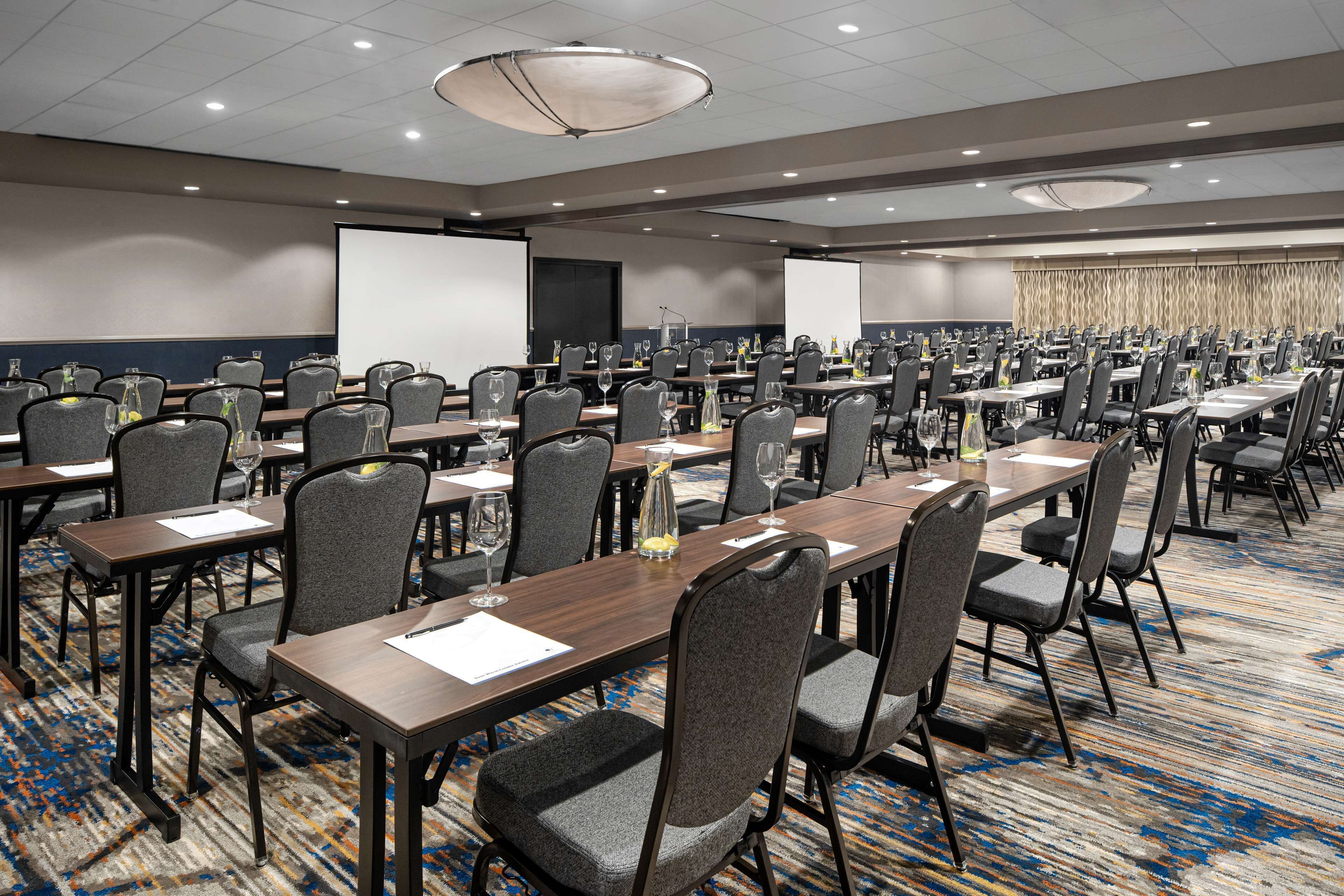 A conference room with multiple tables and chairs, equipped with nameplates and water bottles.