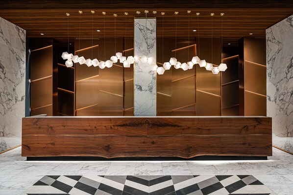 A reception area with a wooden reception desk, marble walls, and a geometric patterned floor.