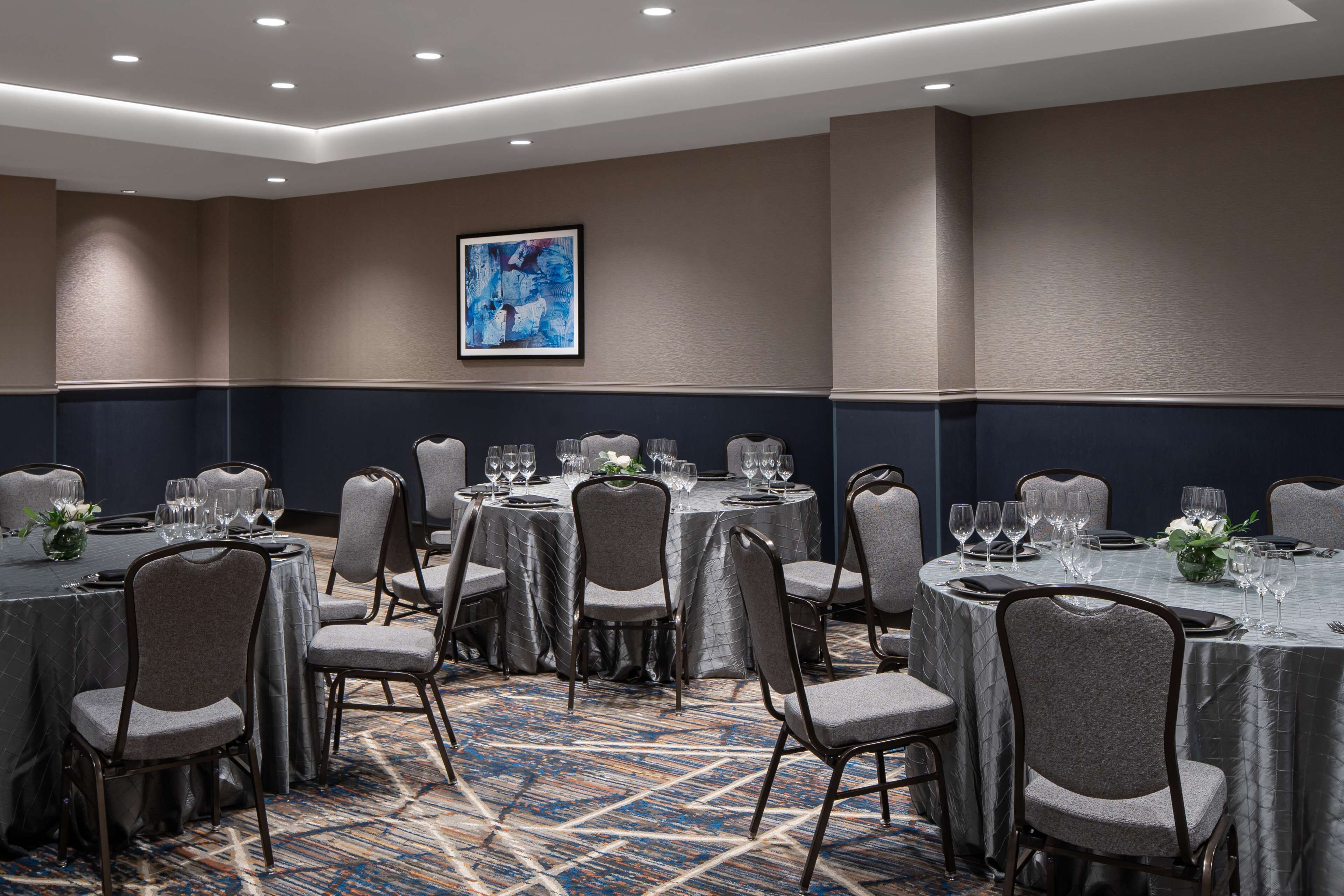 A conference room with round tables, gray chairs, and a patterned carpet.