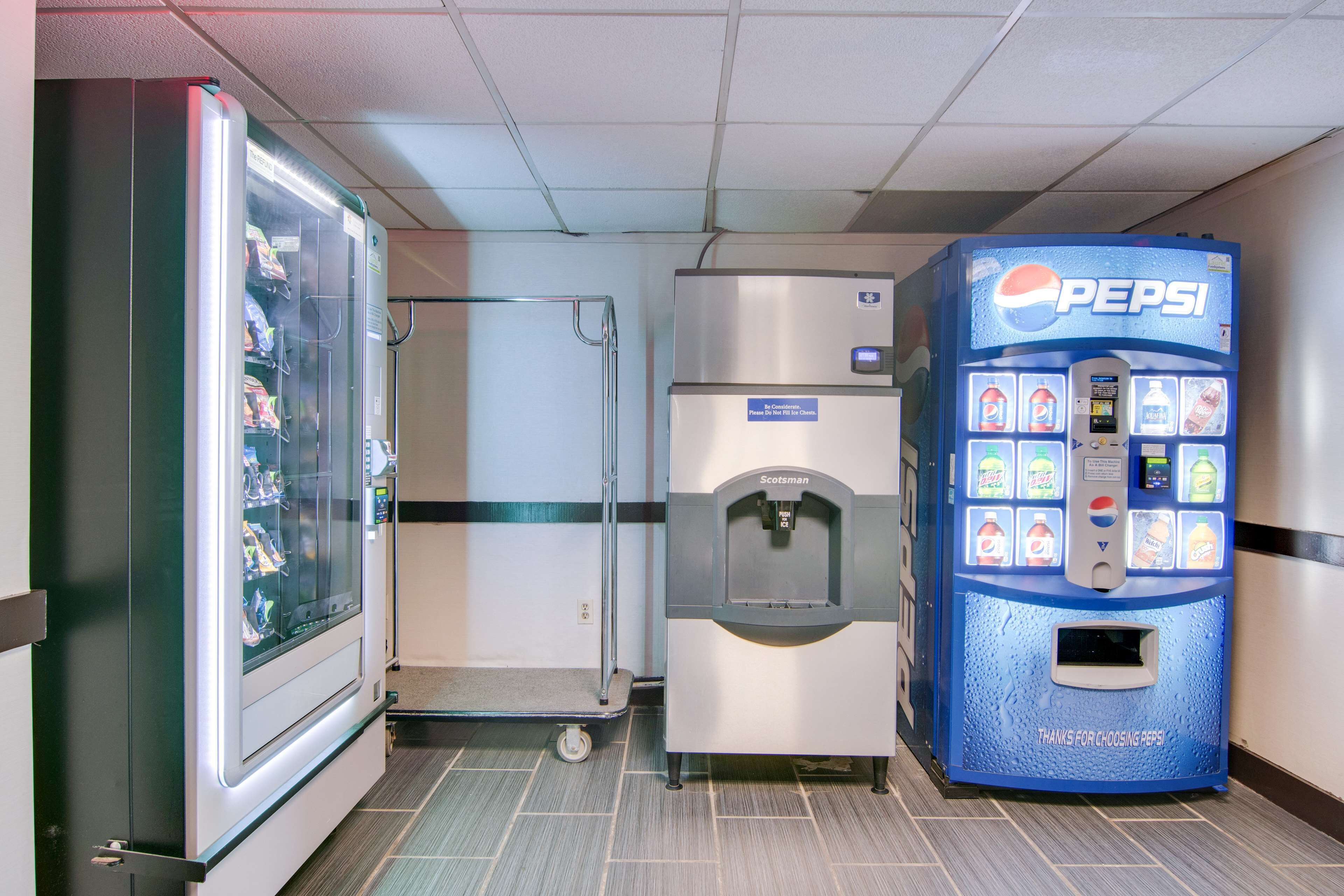 Una máquina expendedora y un refrigerador en un pasillo.