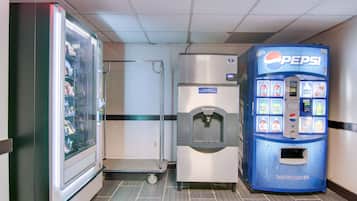 Una máquina expendedora y un refrigerador en un pasillo.