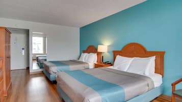 A hotel room with two beds, wooden headboards, and a blue wall.