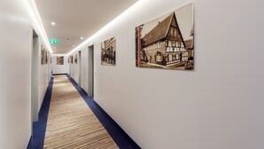 A hallway with wooden flooring and framed pictures on the walls. - Best Western Plus Hotel Stadtquartier Haan (Haan)