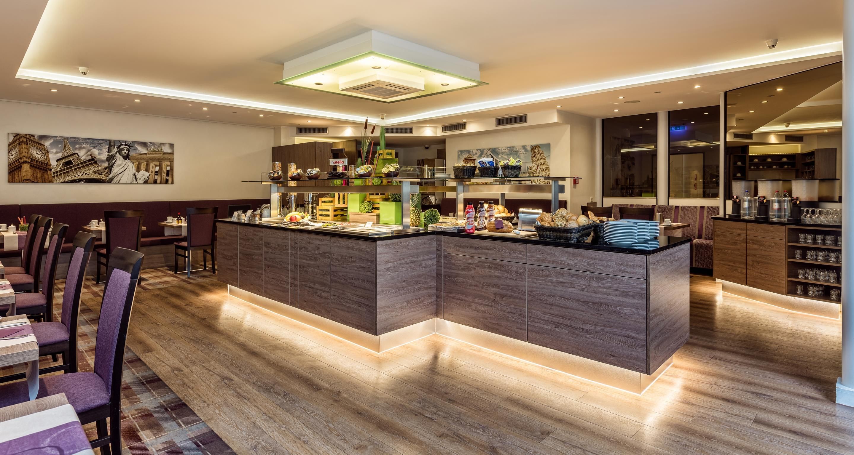 A modern restaurant with a central island counter, wooden flooring, and a buffet area.