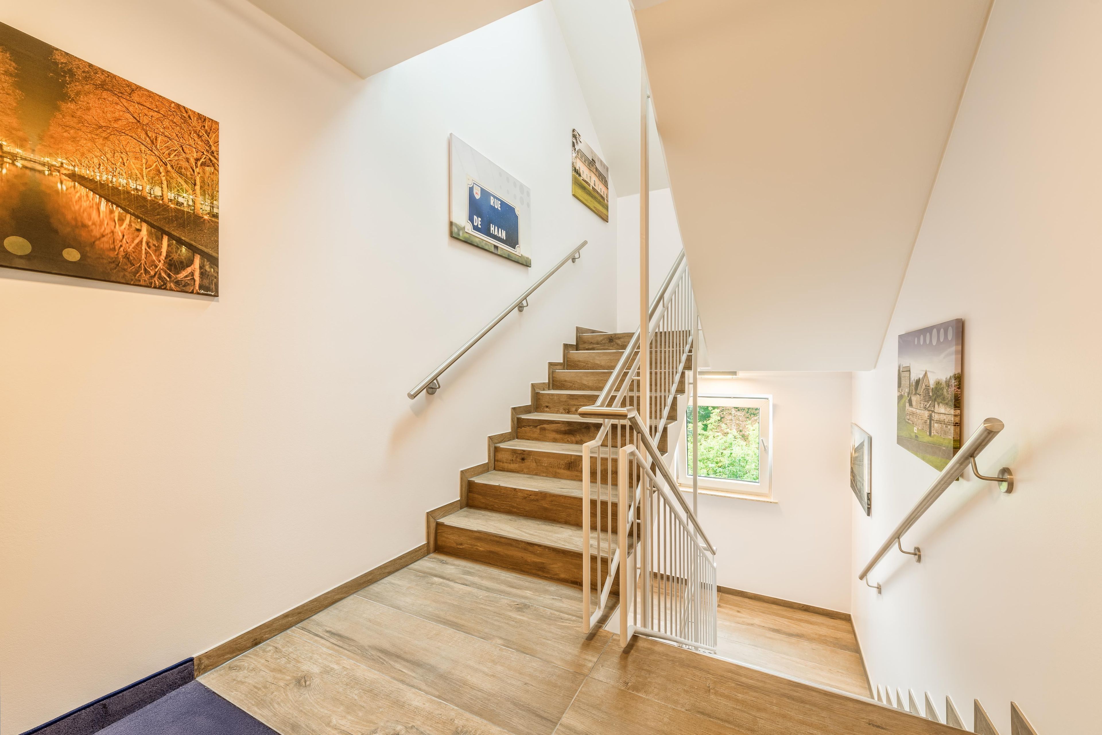 A staircase with wooden steps and metal railings, leading to an upper floor.