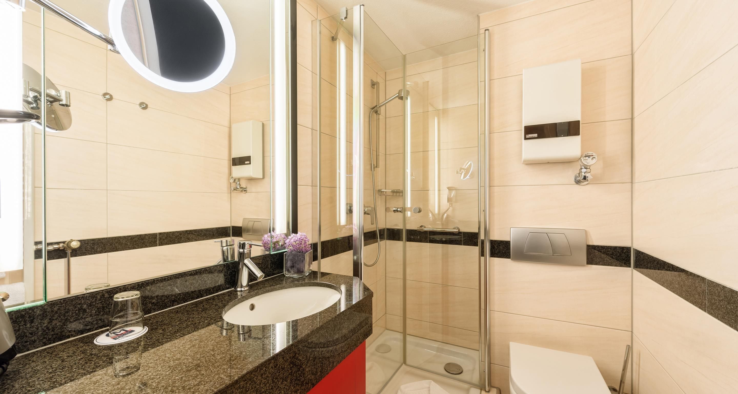 Ein modernes Badezimmer mit Duschkabine aus Glas, Waschbecken mit Marmorplatte und Toilette.