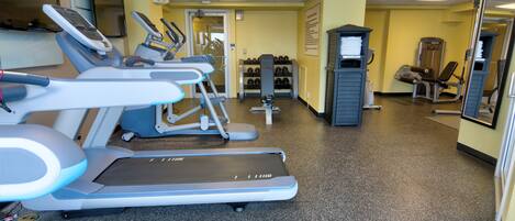 A gym with treadmills, weight machines, and a mirrored wall.