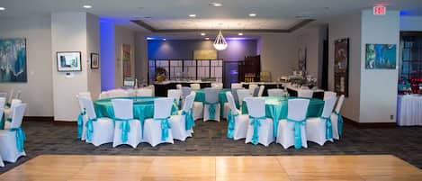 A spacious room with multiple tables and chairs, a dance floor, and a bar area.