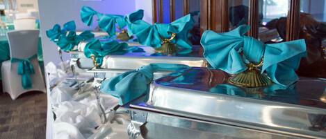 A buffet setup with teal napkins tied to silverware.