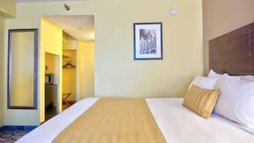 Une chambre d’hôtel avec un lit, un tableau encadré au mur et un couloir menant à la salle de bain.
