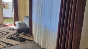 Une pièce avec un canapé, un tapis à motifs et des rideaux.