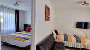 Une chambre avec deux lits, un canapé, un tableau et une télévision.