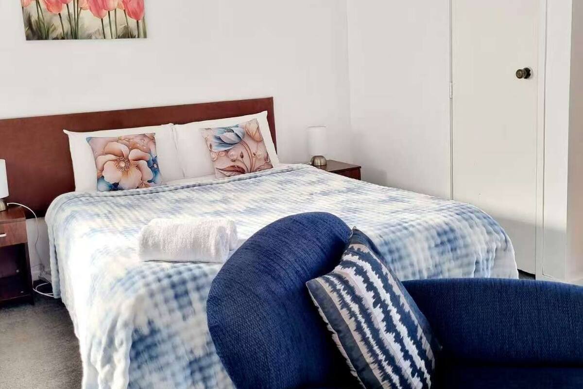 A bedroom with a bed, a nightstand, a chair, and a door.