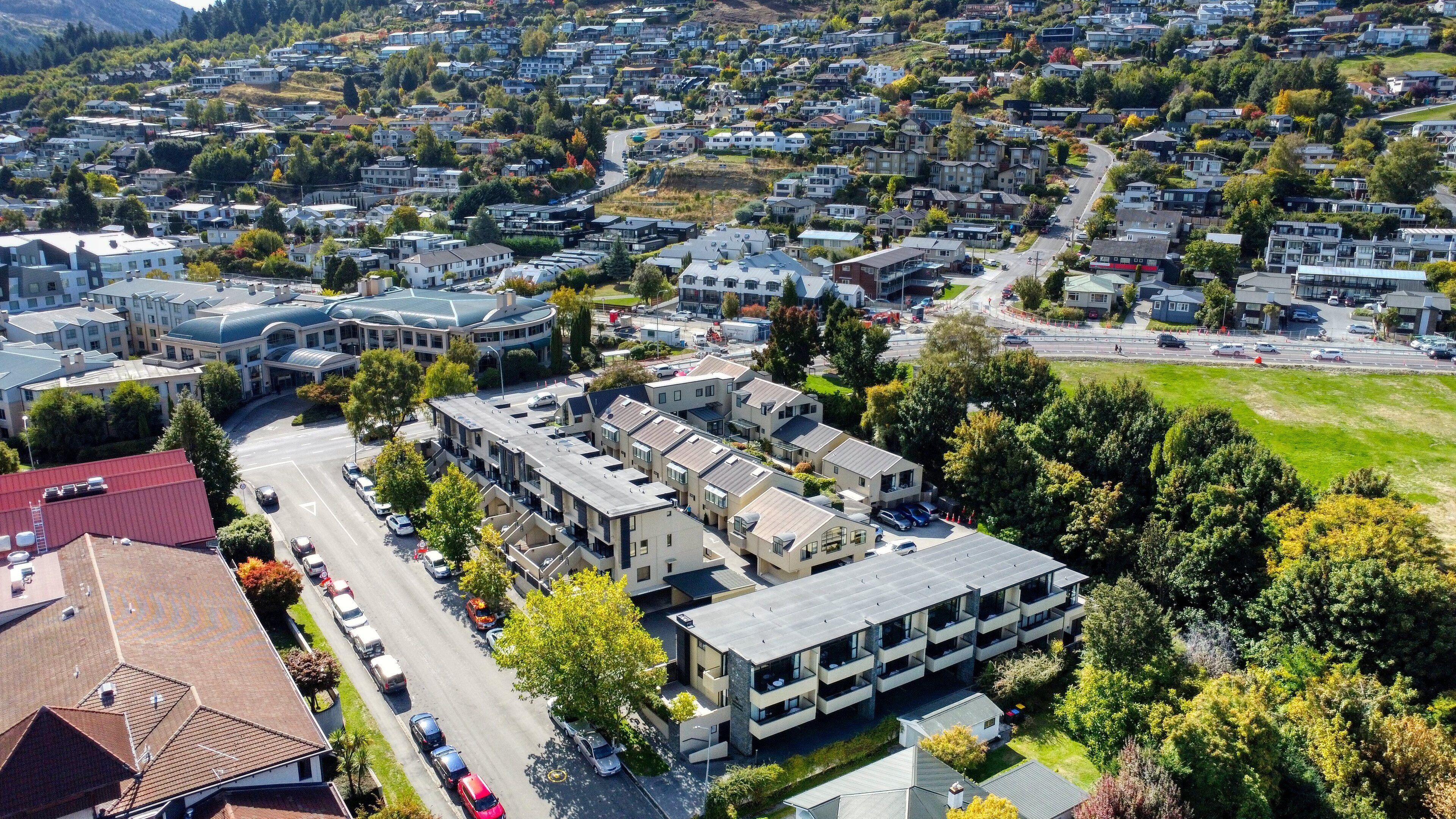 Zona residencial con edificios de apartamentos modernos, una avenida principal y áreas verdes circundantes.