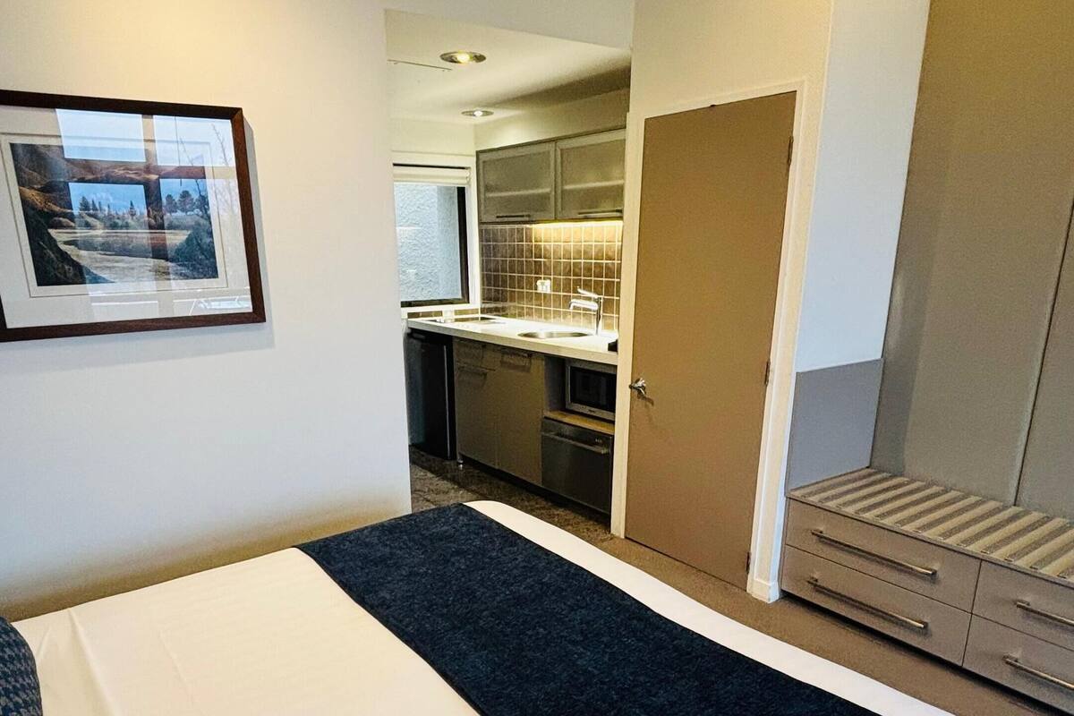 Una habitación de hotel con cama, kitchenette y baño.