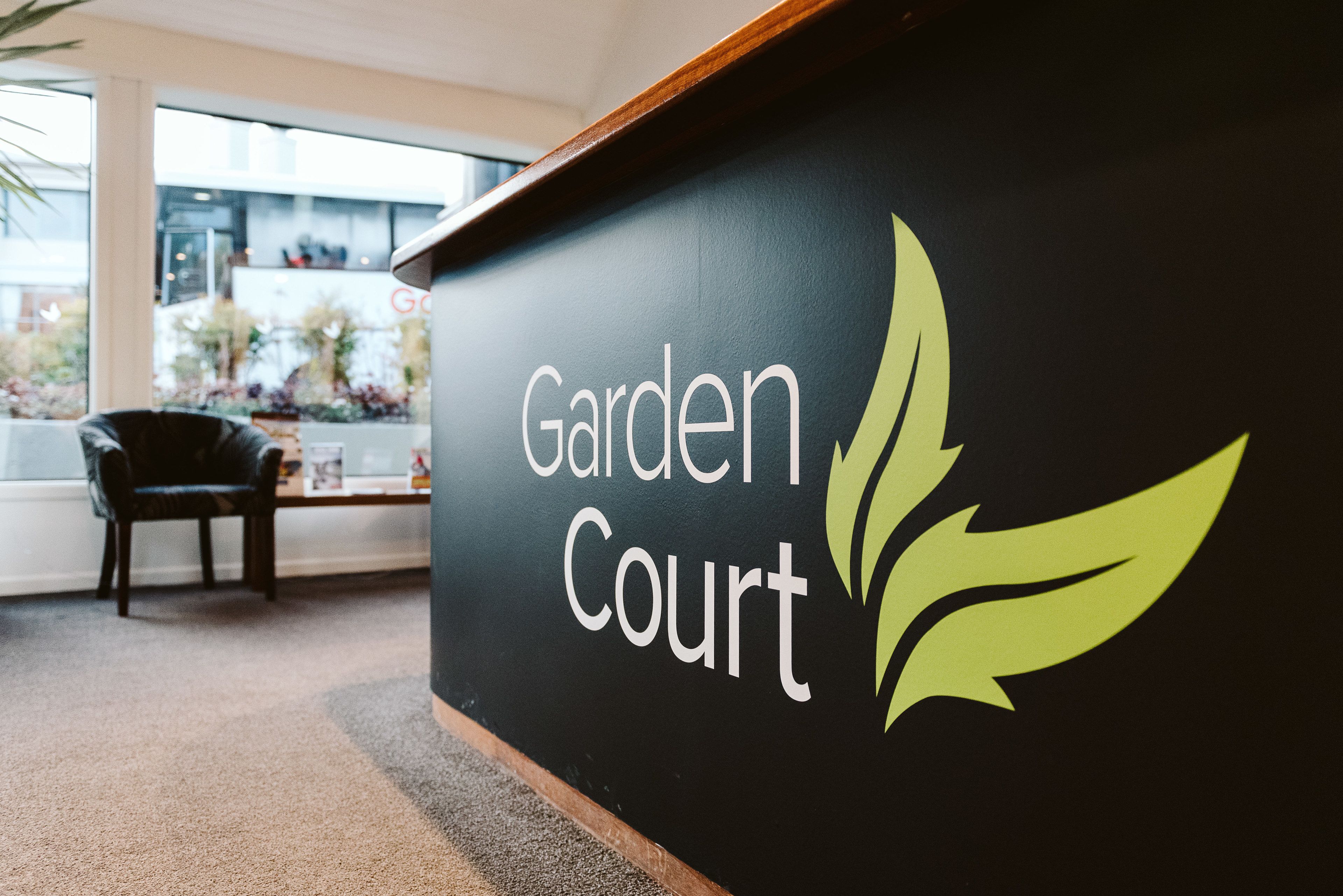A black wall with the words "Garden Court" and a green leaf logo.