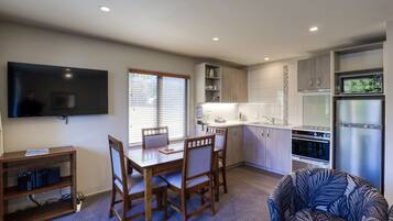 A modern kitchen with a dining area, built-in appliances, and a flat-screen TV.